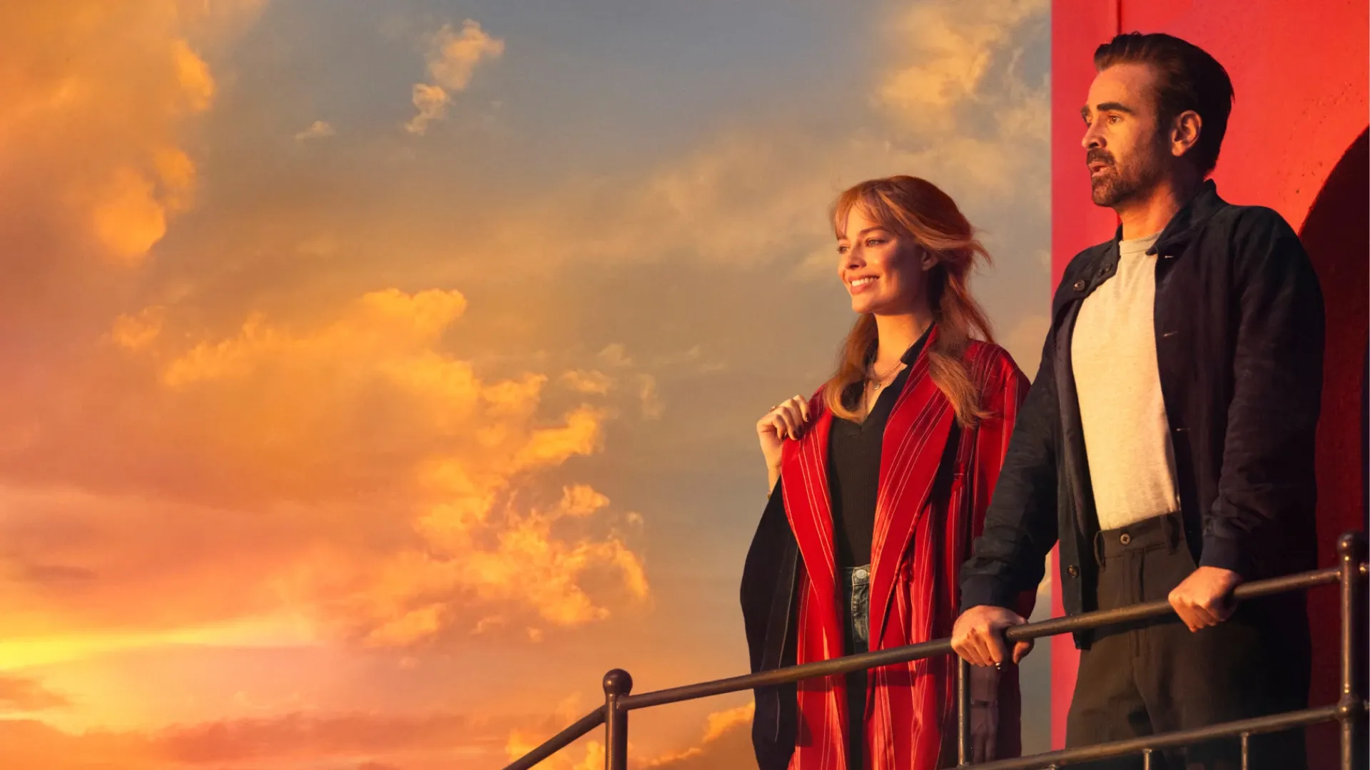 Margot Robbie and Colin Farrell smiling and looking over a railing in the film a Big Bold Beautiful Journey.